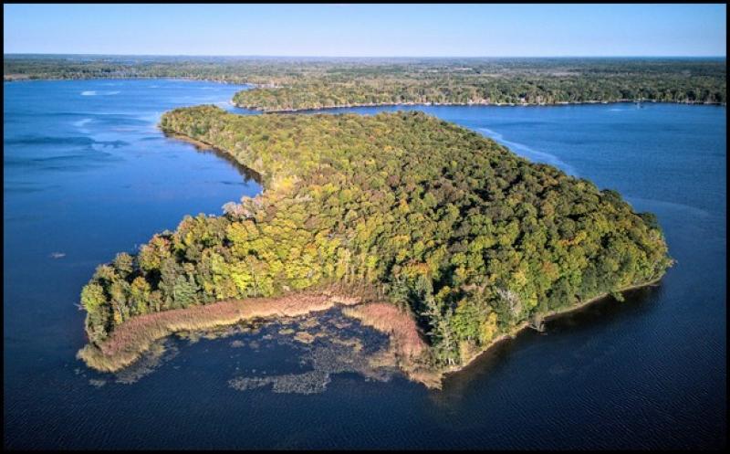 Aerial photograph of an island about the size of several city blocks on lake.