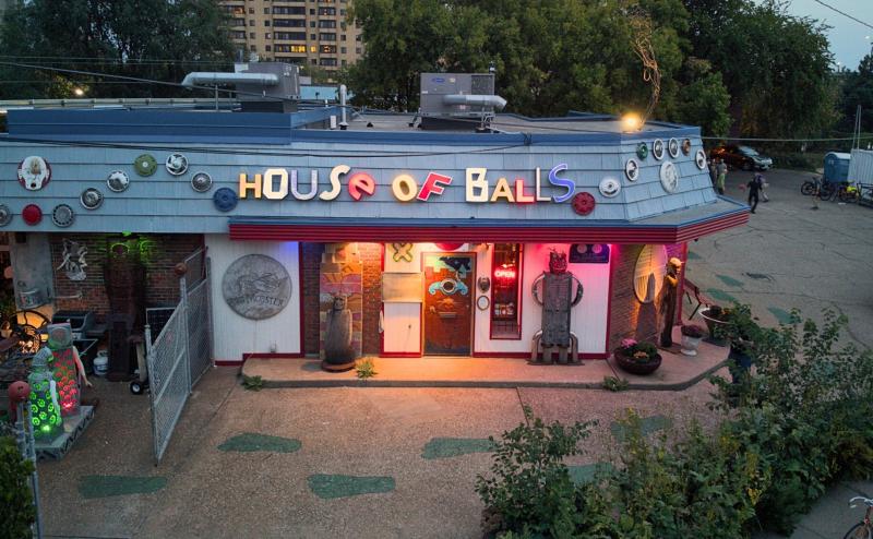 An old gas station is decorated colorfully with with lights and lettering that spells out "House of Balls" 