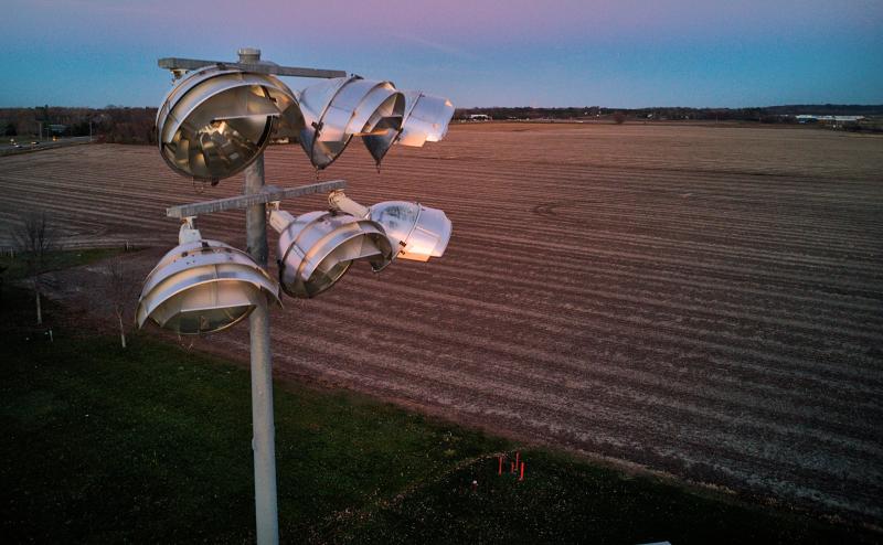 Close up image of some high powered lights with plowed farm fields in background.