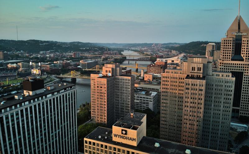 Pittsburgh skyline. Looking down on river with several steel suspension bridges. Wyndham hotel in foreground.