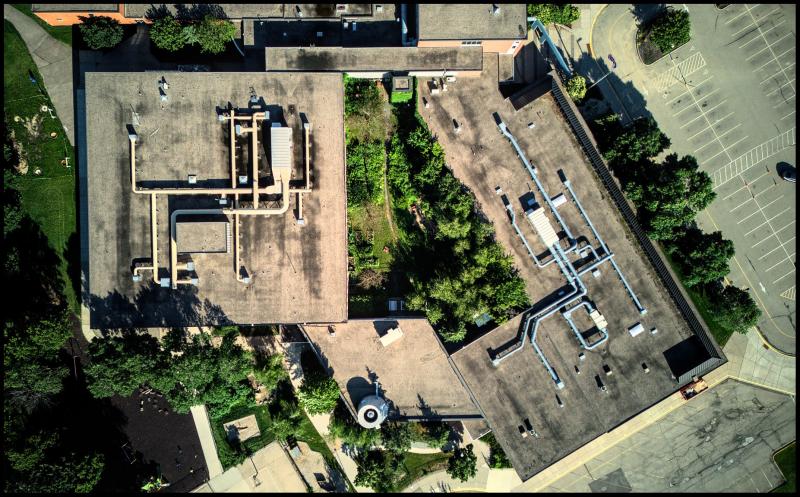 Looking straight down on top of a building with several segments and mix of exposed vents and ducts.