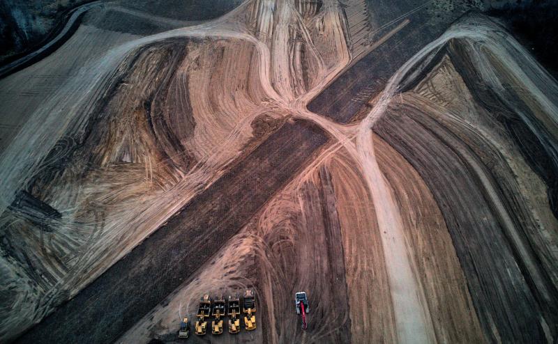Aerial view of a contruction site where lots of dirt has been moved around. The ground is mostly brown, with interesting shapes and patterns generated by the construction equipment.