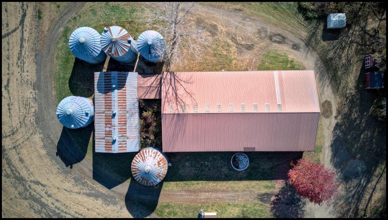 Looking straight down on some farm buildings and metal silos. 