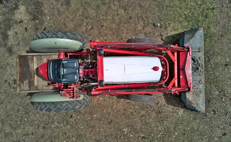 Looking directly down on an old red tractor with black seat. 
